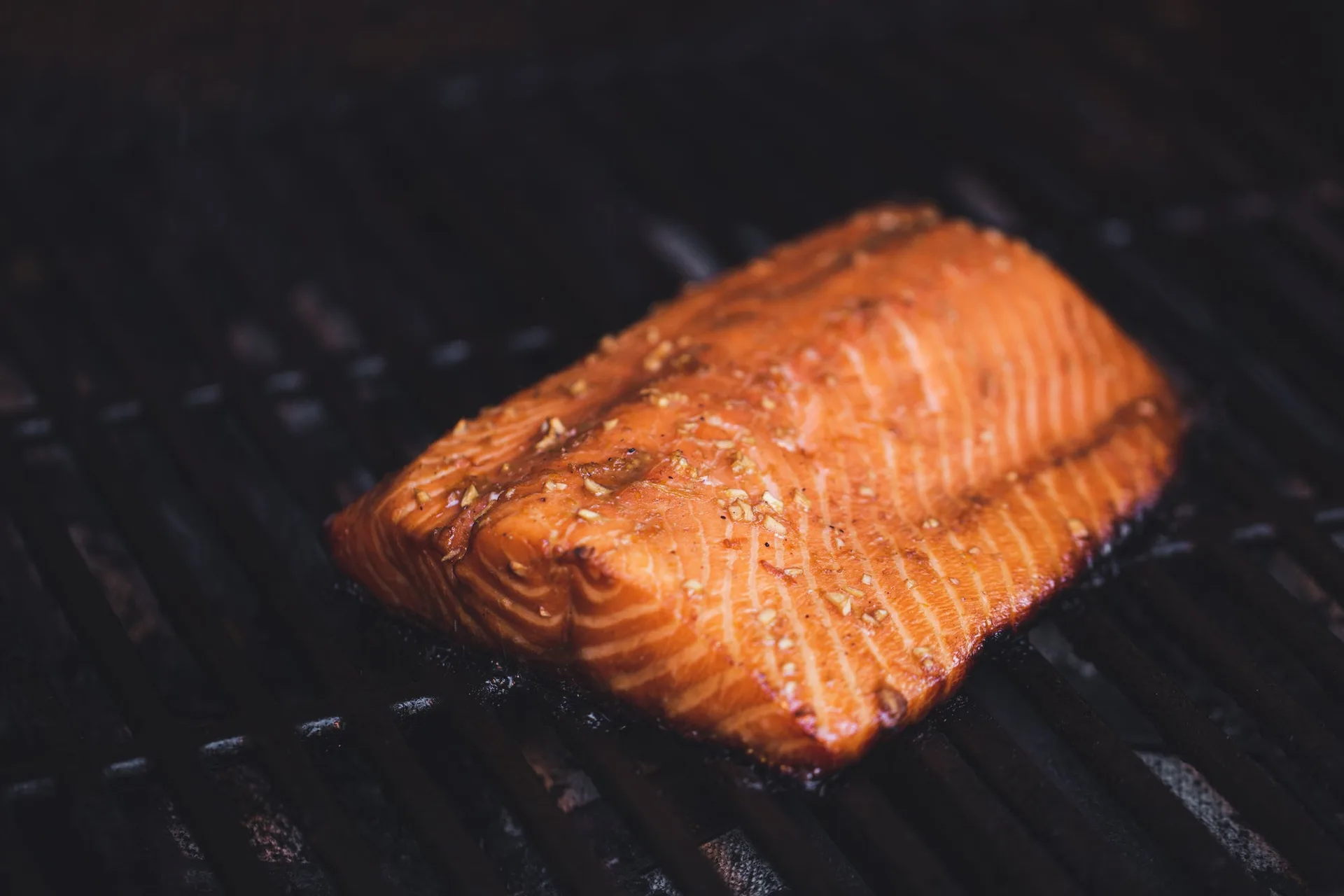 A seasoned salmon fillet cooking on a grill