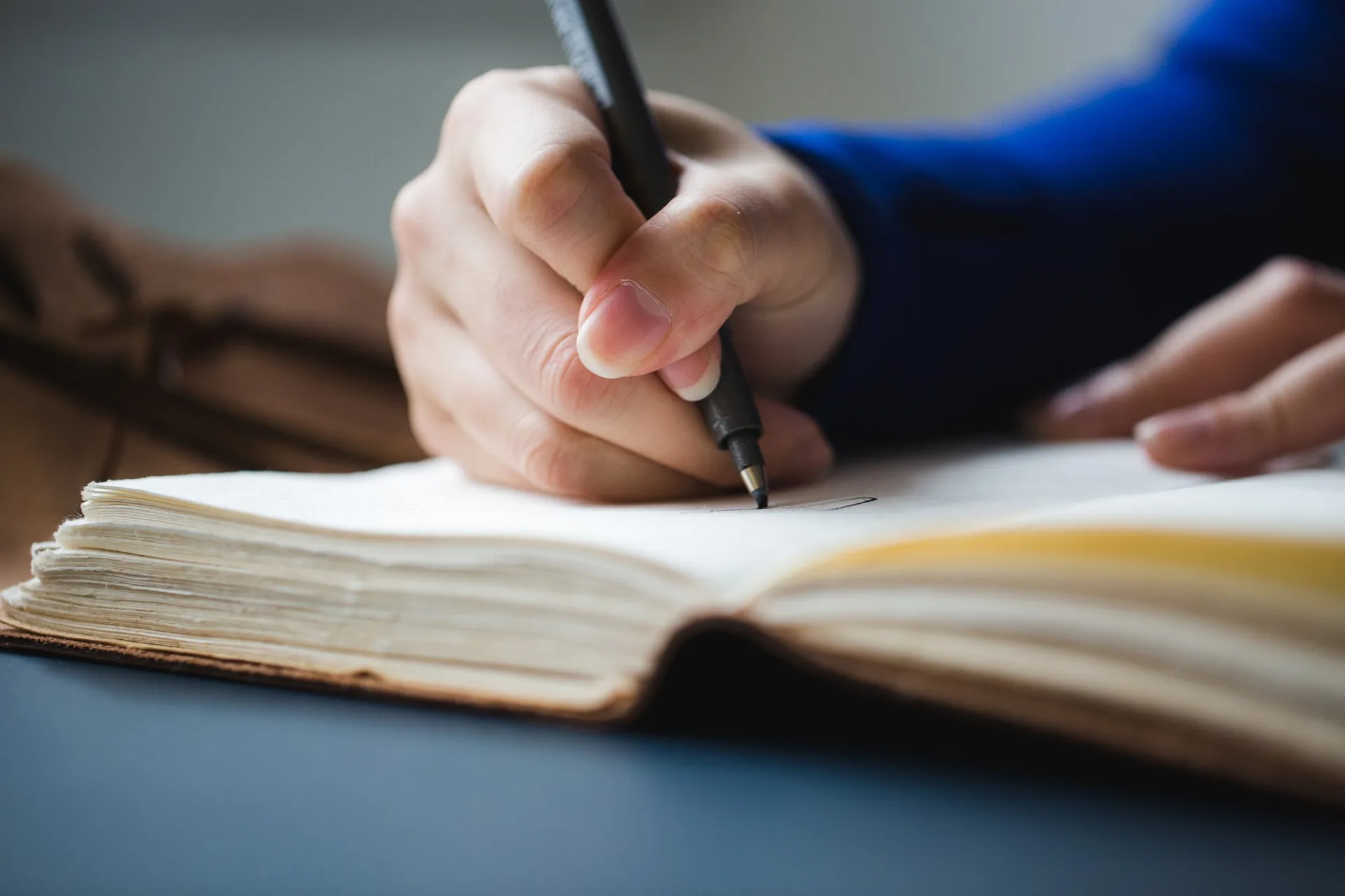 A hand writing in an open journal with a black pen