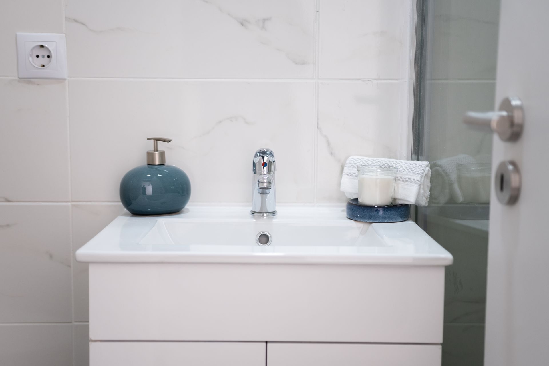 White bathroom sink with a soap dispenser and folded towel