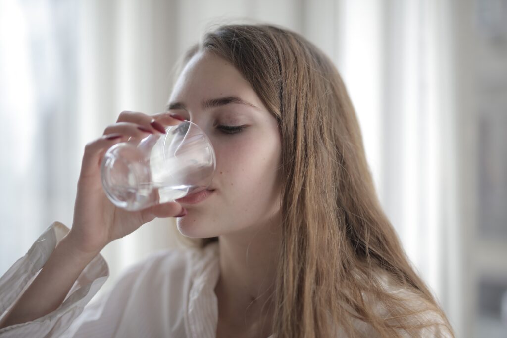 Woman drinking a glass of water, supporting her health while limiting everyday PFAS exposure