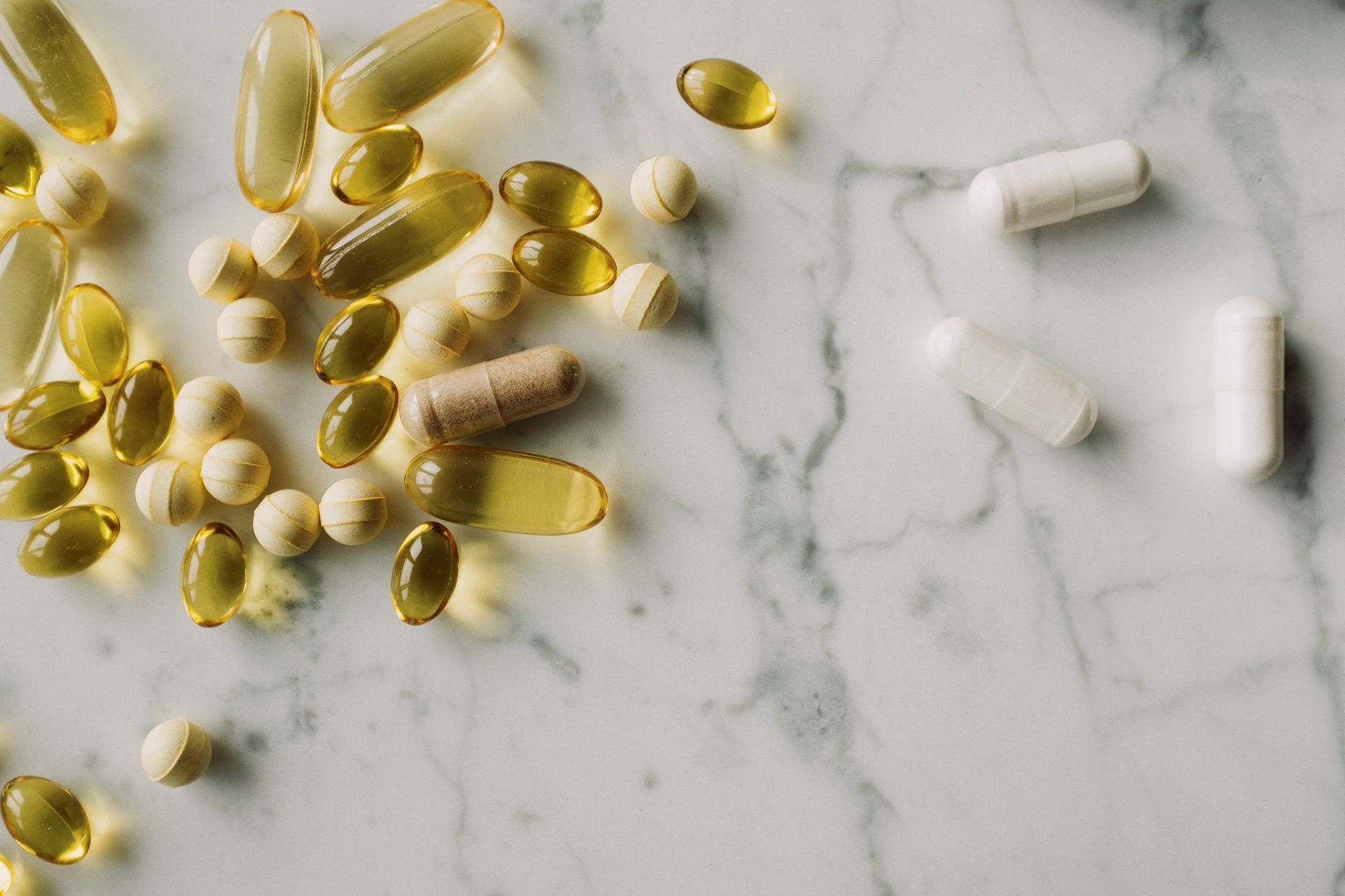 Unbranded capsules and tablets arranged on a light marble surface.