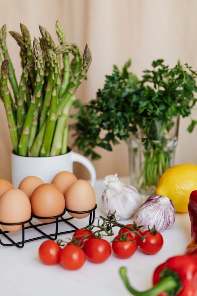 A bright kitchen countertop spread of fresh vegetables, eggs, and herbs used to prep a colorful, whole-food meal