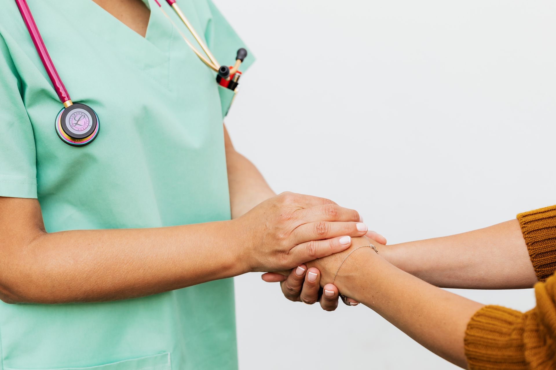 A nurse in scrubs holding a patient's hands