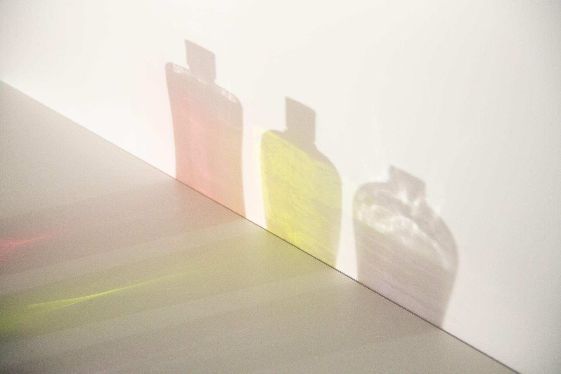 Colorful shadows of small bottles on a light wall