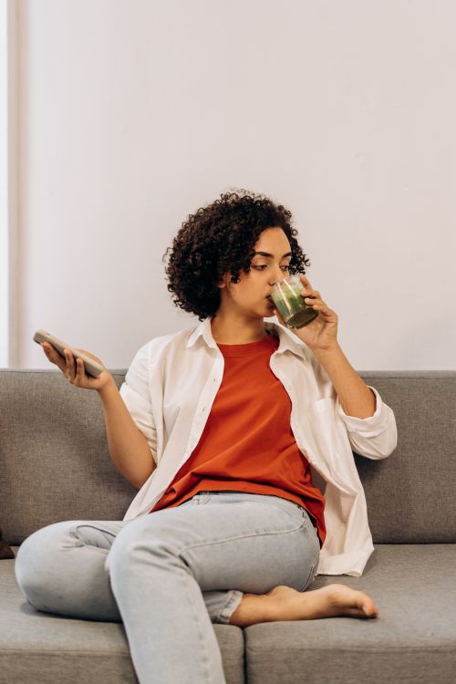 Woman drinking a green wellness smoothie at home, one of the most common ways to take sea moss