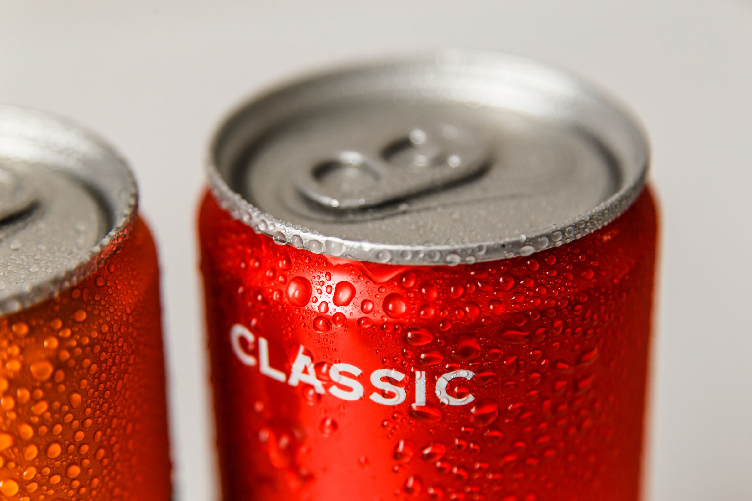 Close-up of cold red cans of drink covered in condensation droplets