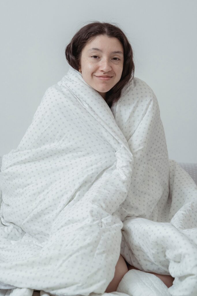 A woman wrapped in a soft blanket resting indoors, calming her stress hormones