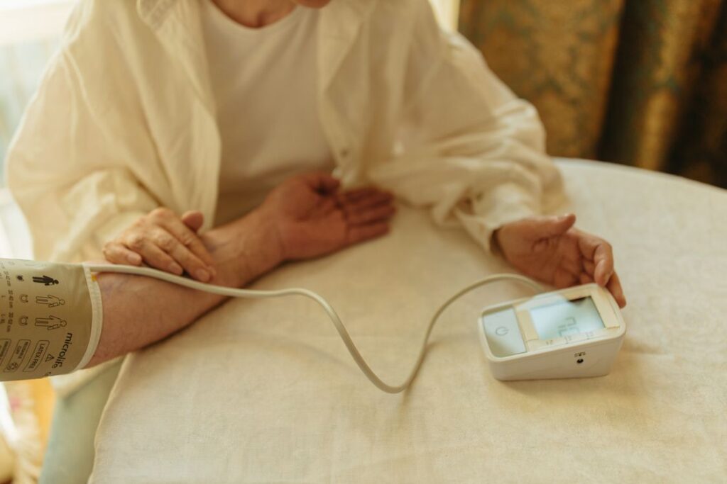 A woman checks her own blood pressure at home with a digital monitor