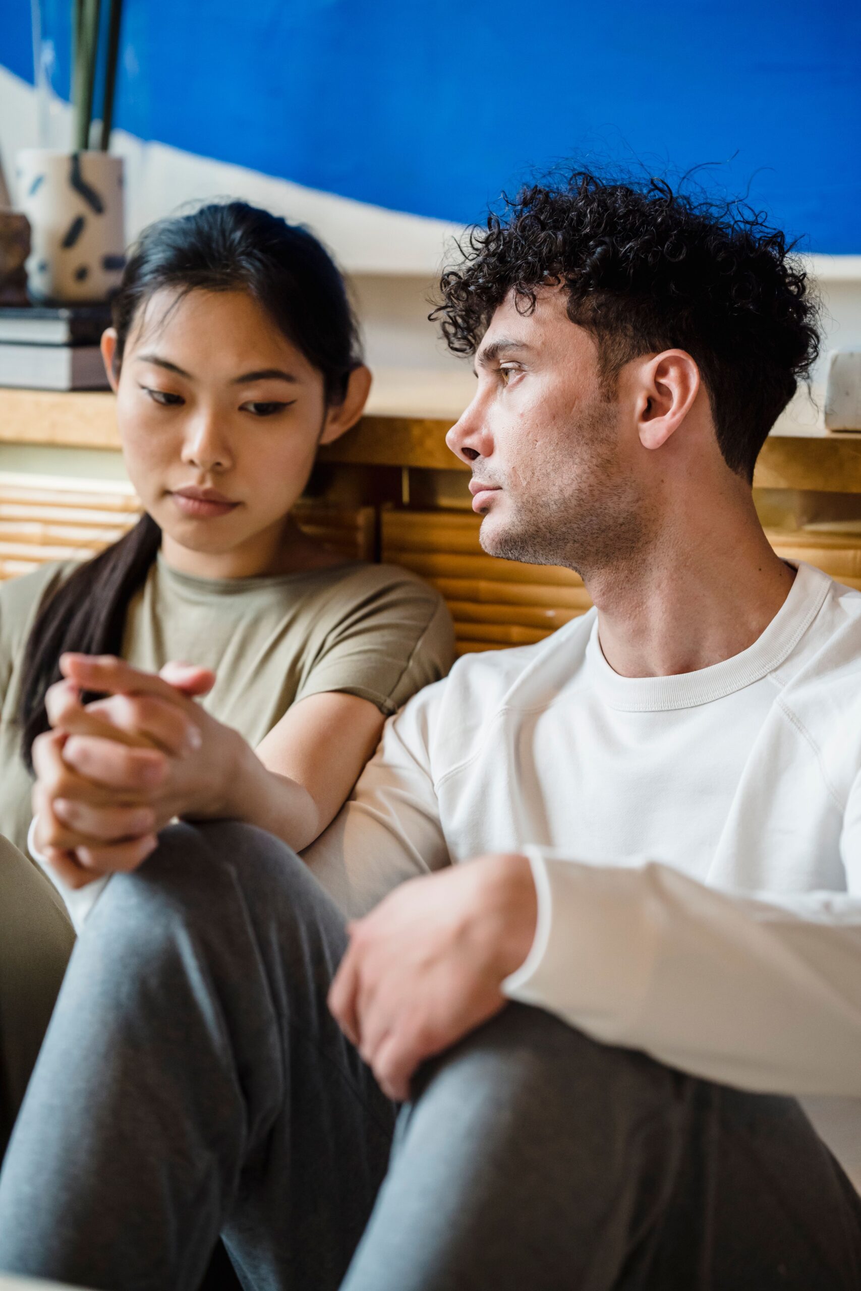 Young couple sitting together holding hands for comfort and support while coping with the stress of trying to conceive