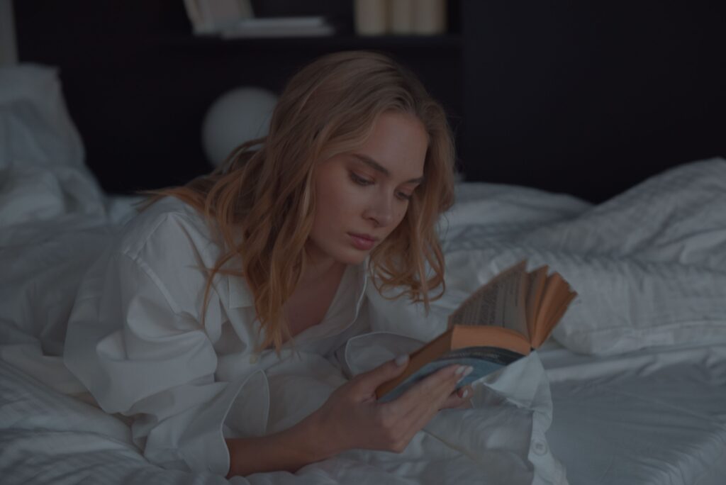 Woman winding down with a book in bed instead of screen time before sleep