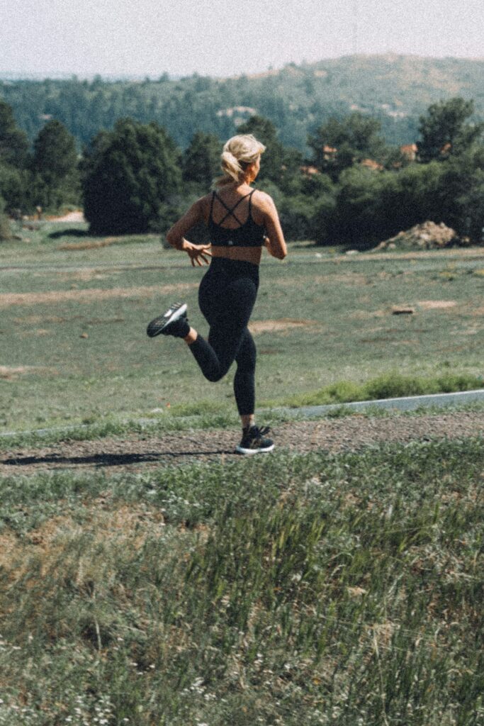 Woman trail running through a grassy field, a heart healthy exercise for women in their 30s