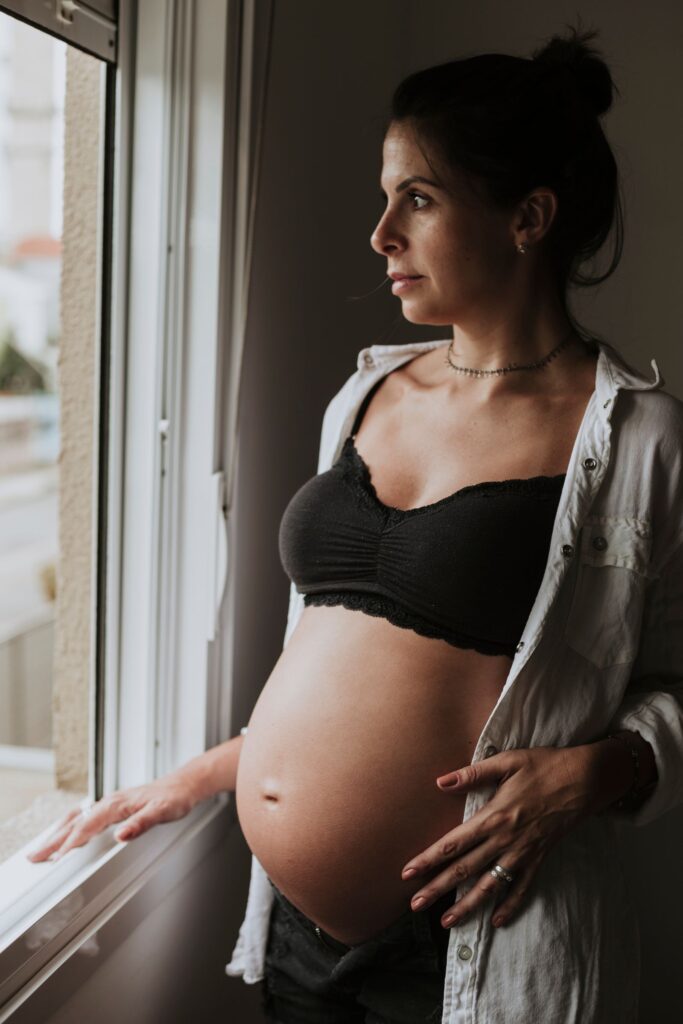 Pregnant woman gazing through a window, illustrating healthy pregnancy prenatal care